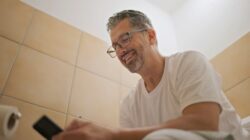 Man using phone in toilet. | Newsreel