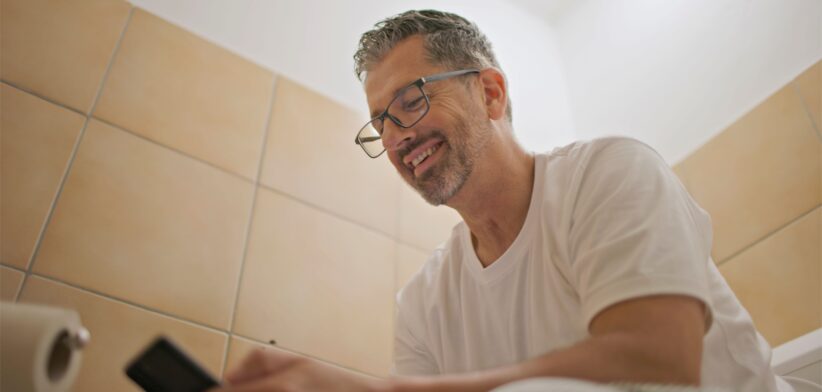 Man using phone in toilet. | Newsreel