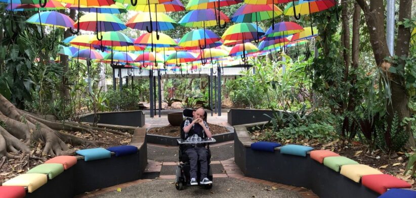 Person on wheelchair under umbrellas. | Newsreel