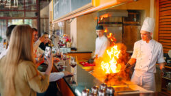 The chef prepares food in front of the visitors in the restaurant.