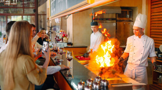 The chef prepares food in front of the visitors in the restaurant.