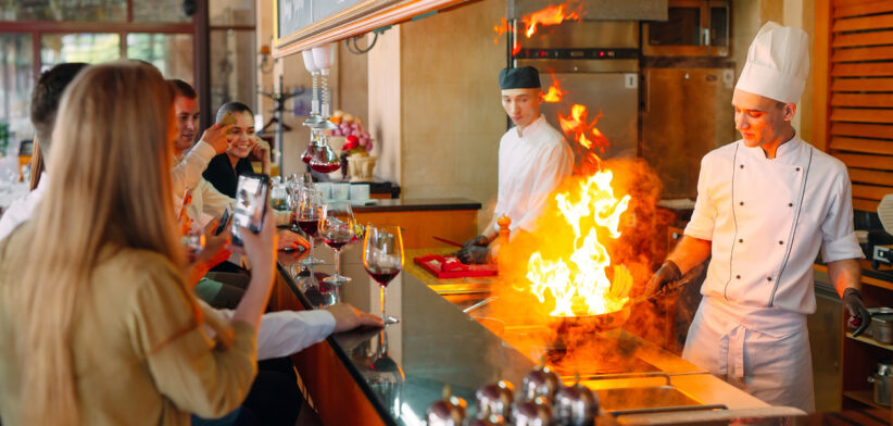 The chef prepares food in front of the visitors in the restaurant.