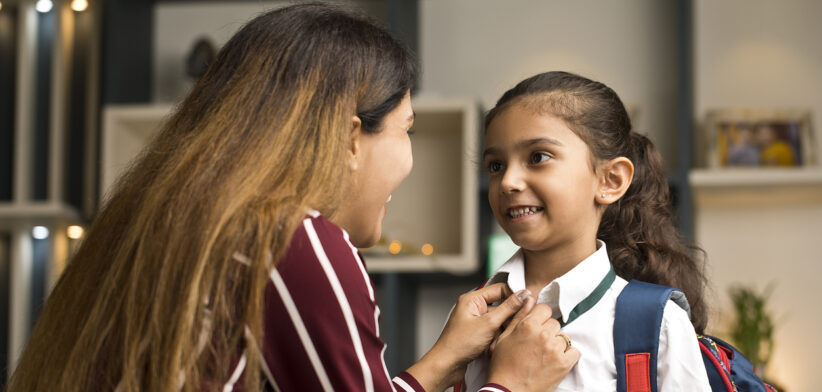 Loving mother getting her daughter ready for school at home