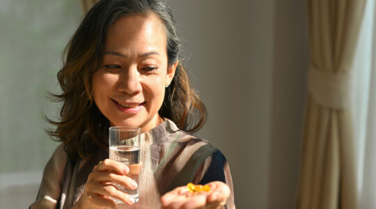 Happy Mature sixty year old female holding omega 3 supplement capsule, Time to take medications.