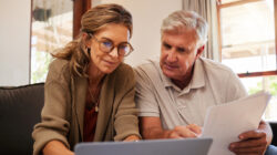 Retirement couple budget, finance and investment planning, loan and paper bills with laptop technology in home. Mature people money, cash savings or legal insurance document report on online bank