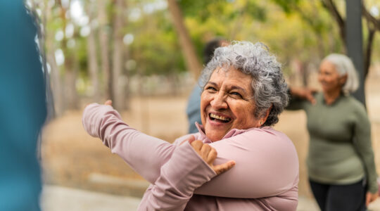 Senior woman stretching and talking friend at public park
