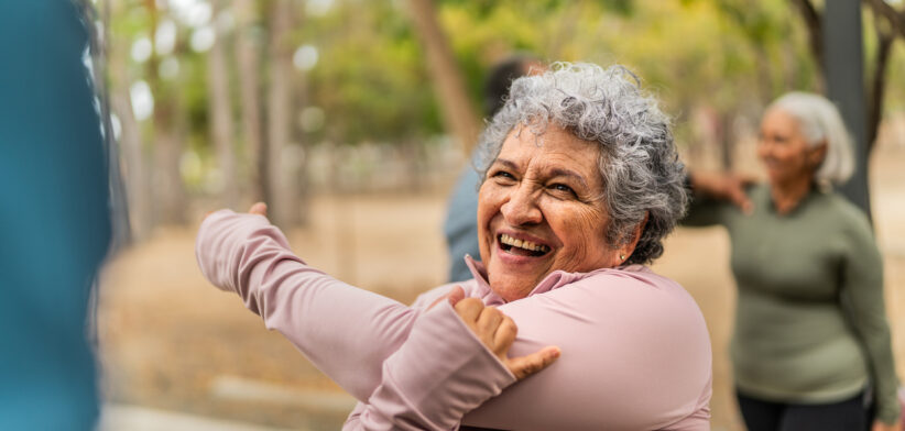 Senior woman stretching and talking friend at public park