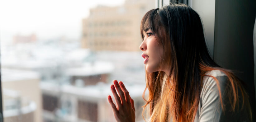 Asian woman sitting in apartment room.