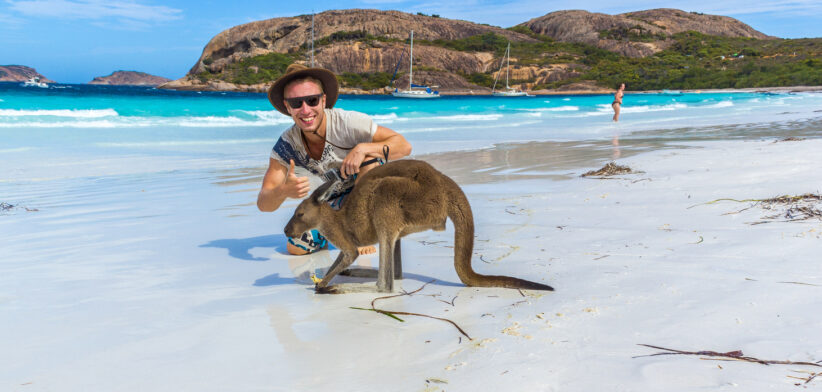 caucasian man with a beautiful Kangaroo at Lucky Bay Beach in the Cape Le Grand National Park near Esperance, Australia