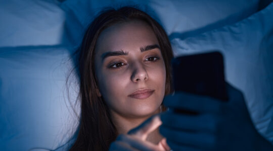 Young woman using smartphone on bed