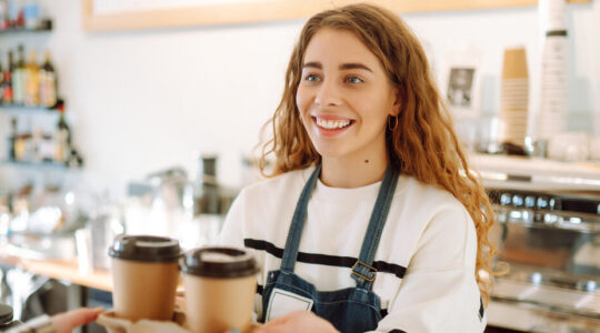 Female barista making coffee in coffee shop counter. Takeaway food.