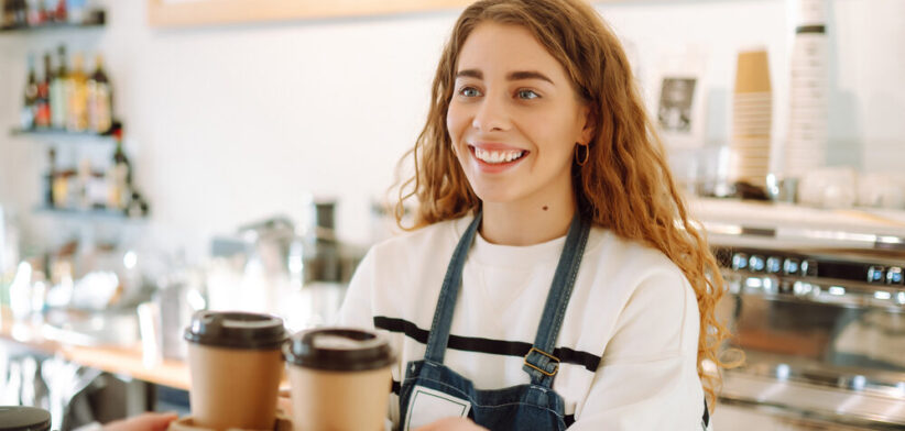 Female barista making coffee in coffee shop counter. Takeaway food.