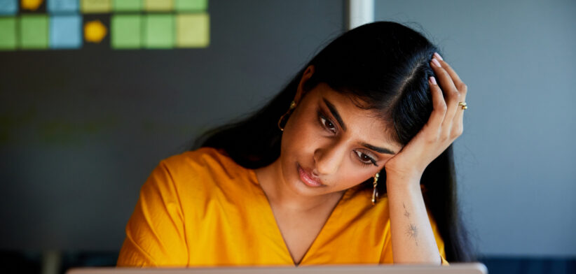Young businesswoman looking stressed while working on laptop in an office