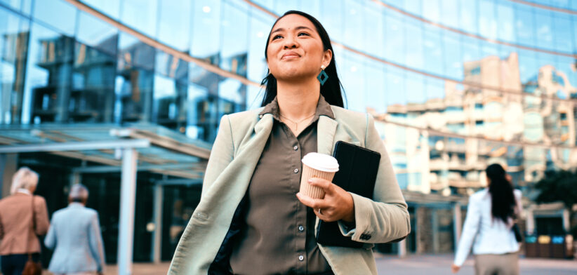 Confident Businesswoman Walking with Coffee Outside Modern Office Building