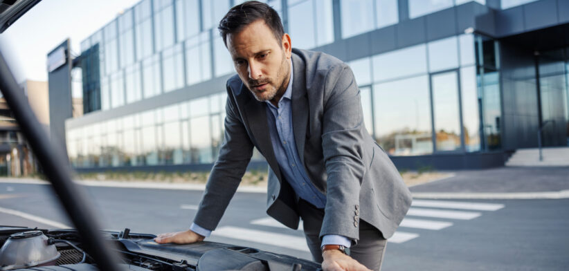 Businessman having car trouble looking at engine