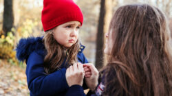 Scared daughter holding mother’s hands in autumn park. Child girl express sad emotions, complain about their own problems
