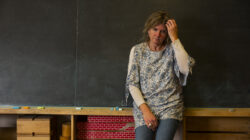 A stressed or depressed mature teacher in a classroom.
