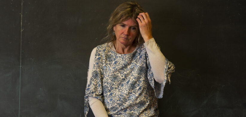A stressed or depressed mature teacher in a classroom.
