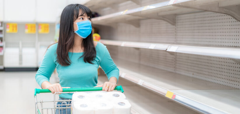 Asian woman looking at Supermarket empty toilet paper shelves amid COVID-19 coronavirus fears, shoppers panic buying and stockpiling toilet paper preparing for a pandemic.