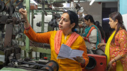 Woman inspecting equipment and workers manufacturing in textile factory