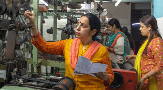 Woman inspecting equipment and workers manufacturing in textile factory