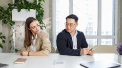 Man and woman sitting in office, holding money at hands. Gender pay gap, unequal salary concept