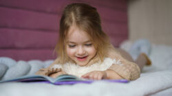 Girl lying in bed and looking at picture book
