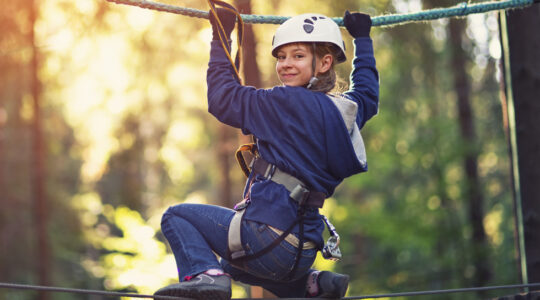 Little girl walking on line in ropes course adventure park
