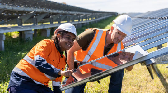 Senior Engineer and Aboriginal Australian Apprentice Working Together On Solar Farm Installation