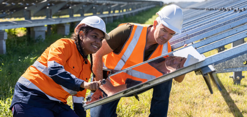 Senior Engineer and Aboriginal Australian Apprentice Working Together On Solar Farm Installation