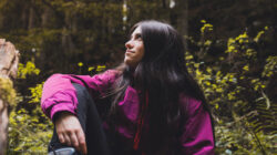 Happy girl resting on a fallen beech tree while hiking through the Irati forest (Navarre, Spain) in Autumn.