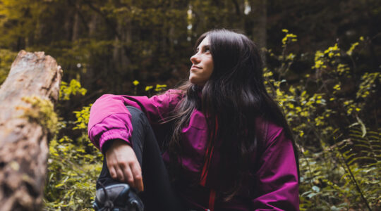 Happy girl resting on a fallen beech tree while hiking through the Irati forest (Navarre, Spain) in Autumn.