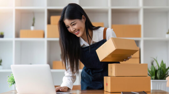 Startup SME small business entrepreneur of freelance Asian woman using laptop and box to receive and review orders online to prepare to pack sell to customers, online sme business ideas