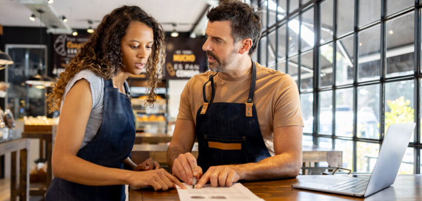 Business owner doing the accountancy at a cafe and talking to his staff