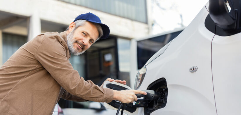 Happy man charging his hybrid truck