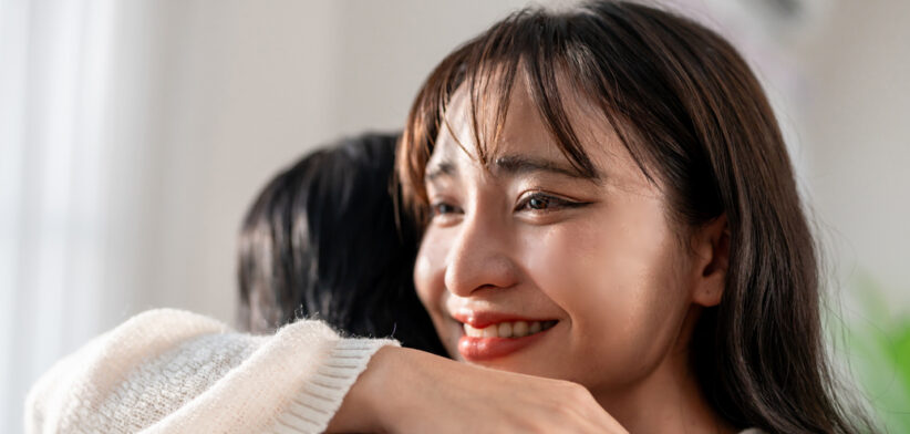 Asian young beautiful couple hugging each other in living room at home. Attractive romantic new marriage man and woman spending leisure time celebrate anniversary and valentine’s day together in house