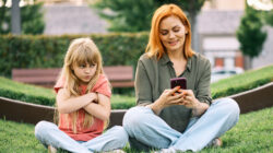 Redheaded Mother Ignoring Upset Blonde Daughter Outdoors