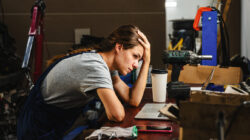 Worried woman entrepreneur in car service shop having business difficulties