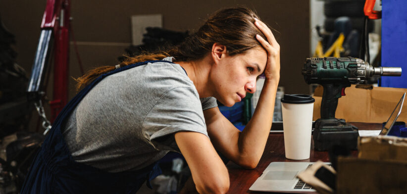 Worried woman entrepreneur in car service shop having business difficulties