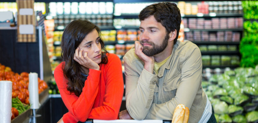 Bored couple with shopping trolley in organic section