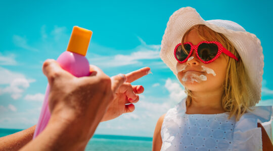 sun protection – mom put suncream on little girl face at beach