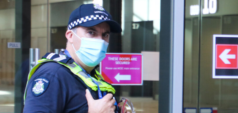 Victoria police officer wearing protective face mask at Covid-19 vaccination hub at Melbourne Convention Centre during lockdown in Victoria, Australia