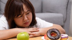 Young beautiful, chubby women choose donut rather than an apple. which can cause overweight or health problem Junk food that can cause obesity and unhealthy for human body.