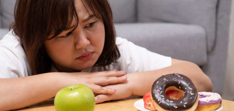 Young beautiful, chubby women choose donut rather than an apple. which can cause overweight or health problem Junk food that can cause obesity and unhealthy for human body.