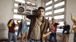 Man with boombox leads group dance session.