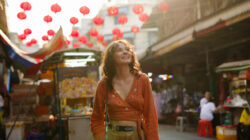 Woman walking on the vibrant street with street food vendors during trip to Thailand