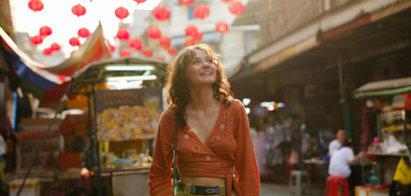 Woman walking on the vibrant street with street food vendors during trip to Thailand