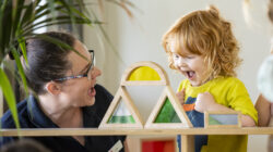 Educator_toddler_stacking_blocks_happy