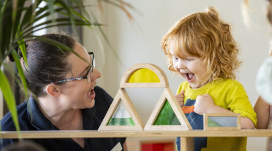 Educator_toddler_stacking_blocks_happy
