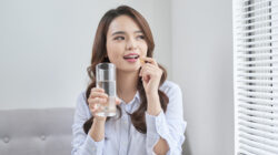 Beautiful Smiling Woman Taking Vitamin Pill. Dietary Supplement